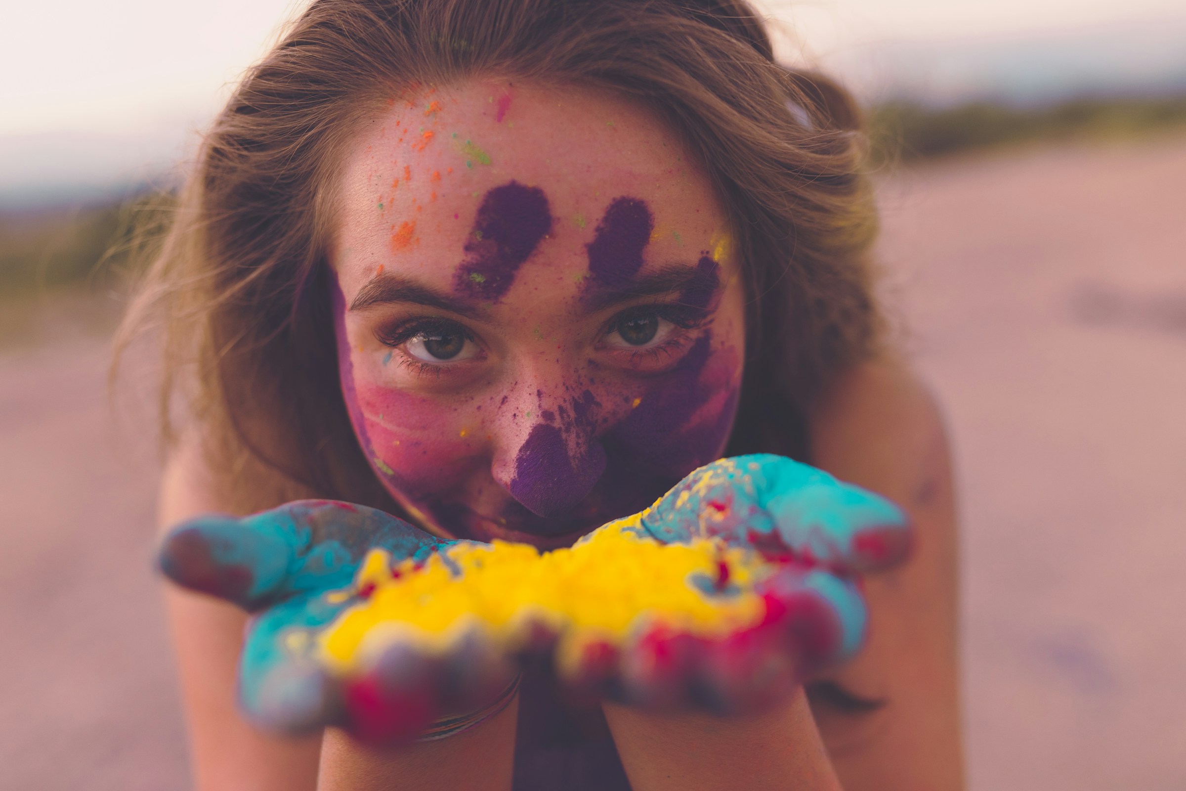 Young person holding powdered pigment in hand with paint on face